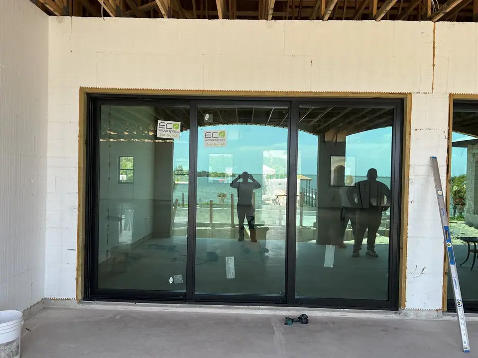 Oversized black-frame impact sliding glass door with water view