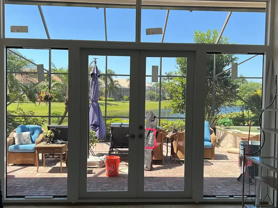 Impact French doors with transom windows opening to a pool deck