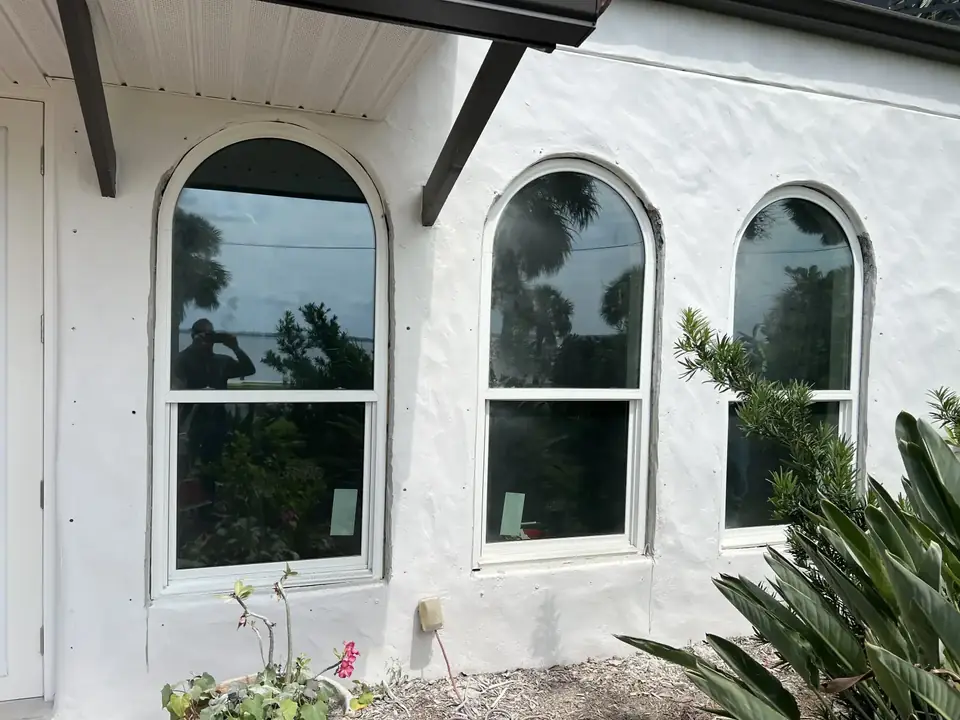 Arched-top impact windows on a white stucco home